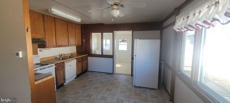 kitchen with white appliances, ceiling fan, brown cabinets, light floors, and a sink