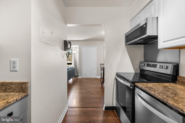 kitchen with stone countertops, appliances with stainless steel finishes, white cabinets, and dark wood-style flooring