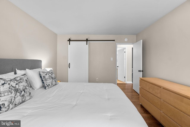 bedroom with a barn door and dark wood-style flooring