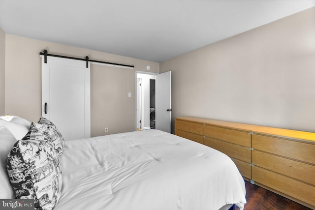 bedroom with a barn door and dark wood-style flooring