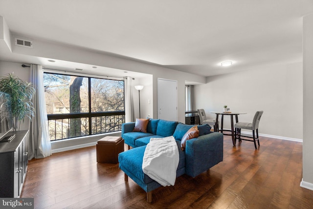 living room featuring dark wood-style floors, visible vents, and baseboards