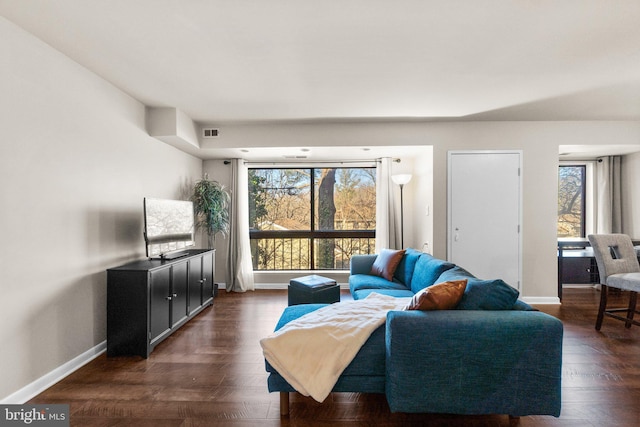 living room with dark wood finished floors, visible vents, plenty of natural light, and baseboards