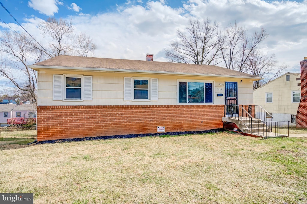 view of front of home with crawl space, a front yard, a chimney, and brick siding