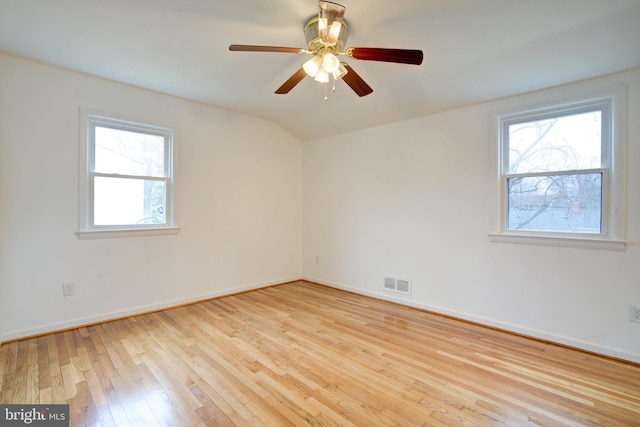 empty room featuring visible vents, a ceiling fan, hardwood / wood-style flooring, baseboards, and vaulted ceiling