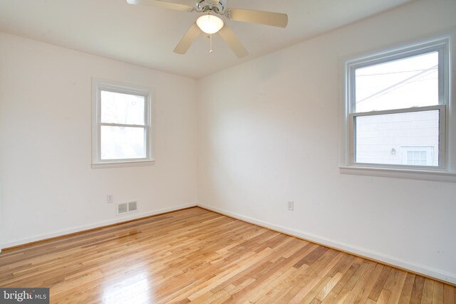 unfurnished room with ceiling fan, visible vents, baseboards, and hardwood / wood-style floors