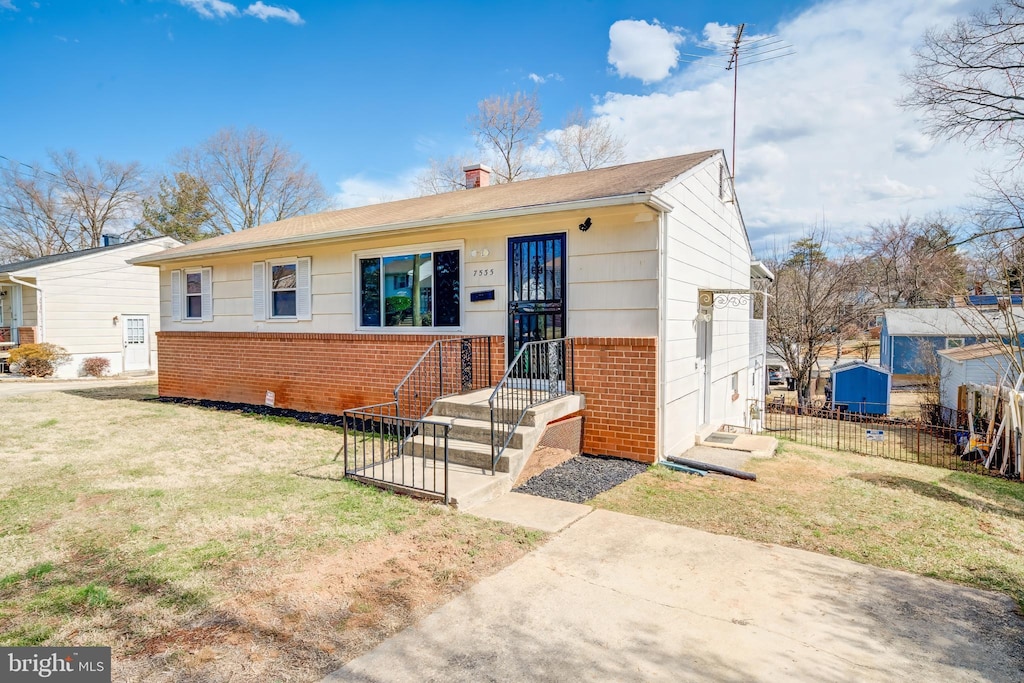 view of front facade with brick siding, fence, a chimney, and a front lawn