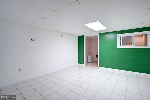 unfurnished room featuring light tile patterned flooring, a paneled ceiling, and baseboards