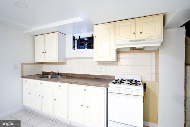 kitchen featuring tasteful backsplash, under cabinet range hood, light tile patterned floors, white gas range, and a sink