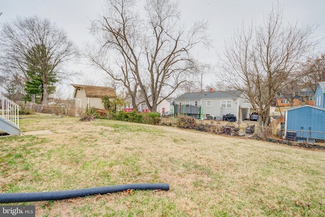 view of yard featuring a storage shed, an outbuilding, fence, and a residential view