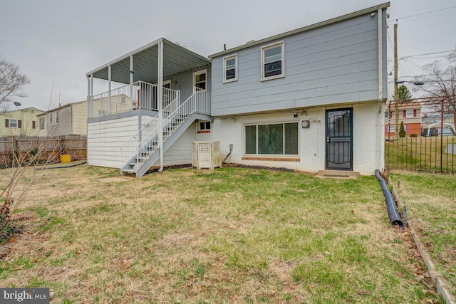 rear view of house with stairway, a yard, and fence