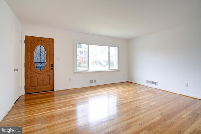 foyer with light wood-type flooring, visible vents, and baseboards