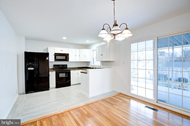 kitchen featuring visible vents, black appliances, light wood-style flooring, white cabinets, and a chandelier