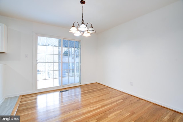 unfurnished dining area featuring a notable chandelier, visible vents, baseboards, and light wood-style floors