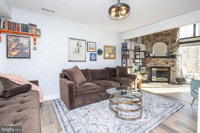 living room featuring visible vents, a fireplace, baseboards, and wood finished floors