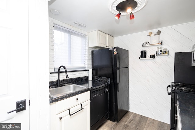 kitchen with wood finished floors, a sink, visible vents, black appliances, and dark countertops