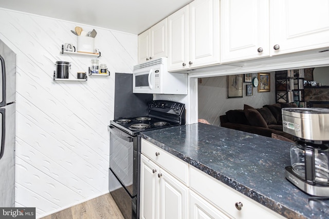 kitchen featuring white cabinets, dark stone counters, white microwave, wood finished floors, and black / electric stove