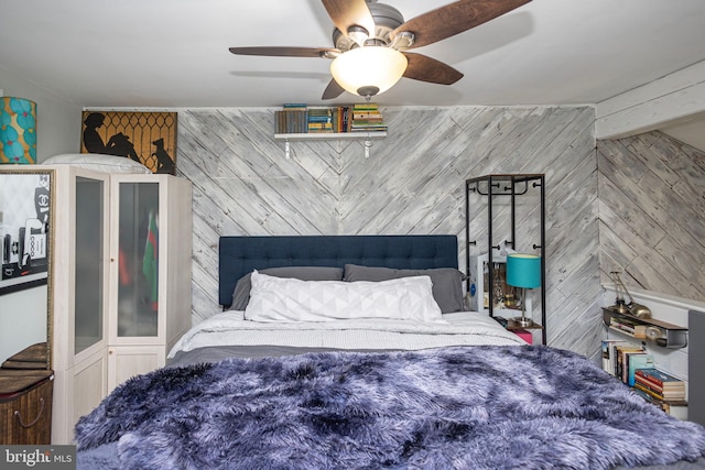 bedroom with a ceiling fan and wooden walls