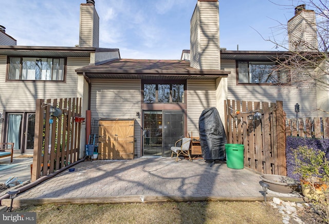 rear view of house with a patio, a chimney, and fence