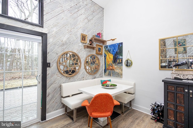 dining area featuring breakfast area, a towering ceiling, baseboards, and wood finished floors