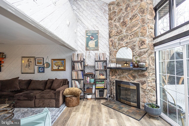 living area with a high ceiling, wood walls, a fireplace, and wood finished floors