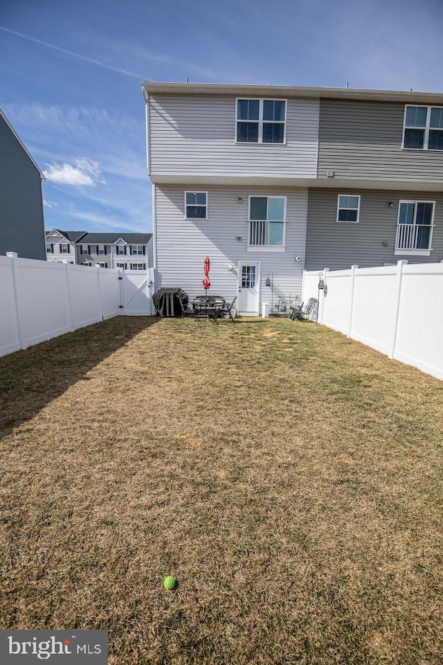 rear view of house featuring a yard and a fenced backyard