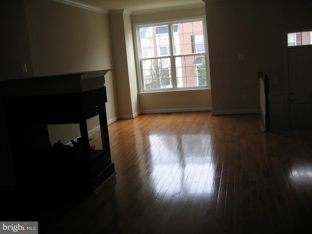 living room featuring hardwood / wood-style floors, baseboards, and crown molding