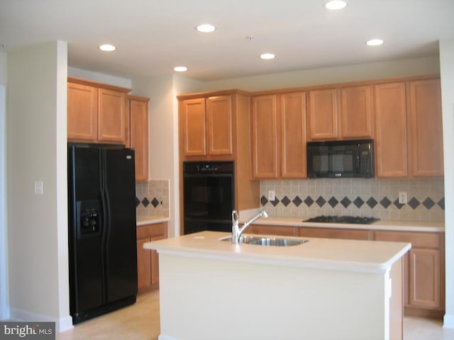 kitchen featuring a kitchen island with sink, light countertops, black appliances, a sink, and recessed lighting