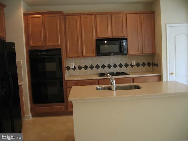 kitchen with a sink, black appliances, backsplash, and light countertops