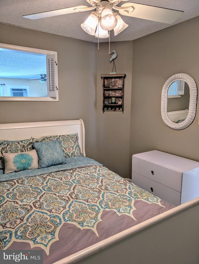 bedroom with ceiling fan and a textured ceiling