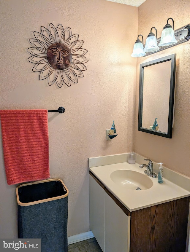 bathroom with a textured wall and vanity