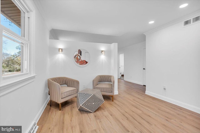 living area featuring visible vents, crown molding, baseboards, and wood finished floors