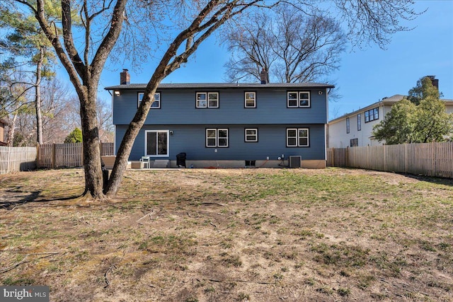 back of house with a yard, a fenced backyard, central AC, and a chimney