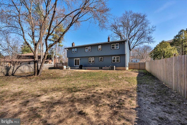 back of property with a yard, central air condition unit, a chimney, and a fenced backyard