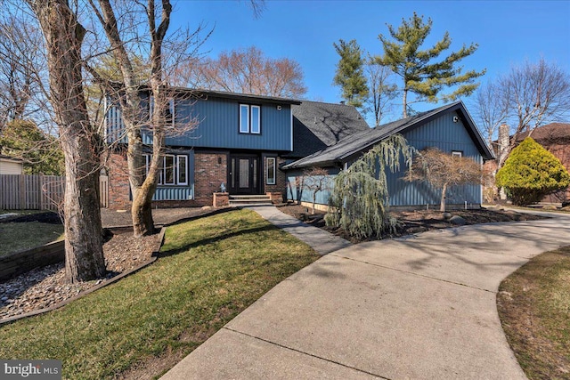 view of front facade featuring brick siding, concrete driveway, a front lawn, and fence