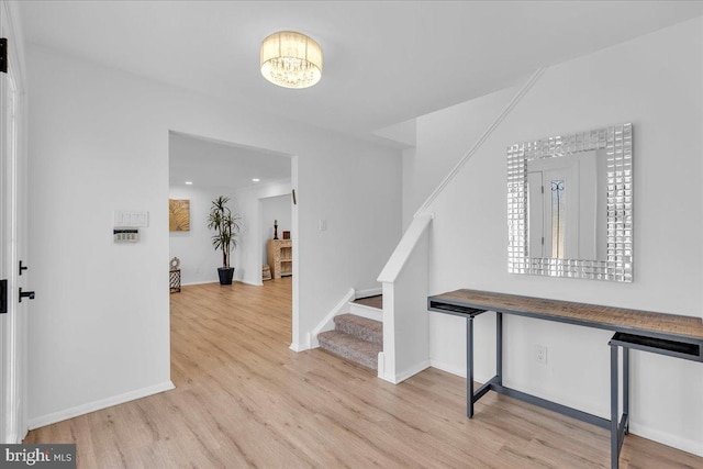 hall featuring a chandelier, stairs, baseboards, and wood finished floors