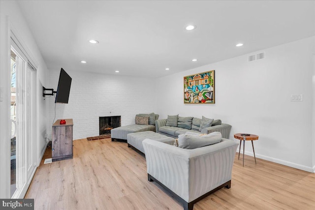 living area with visible vents, recessed lighting, light wood-style floors, baseboards, and a brick fireplace