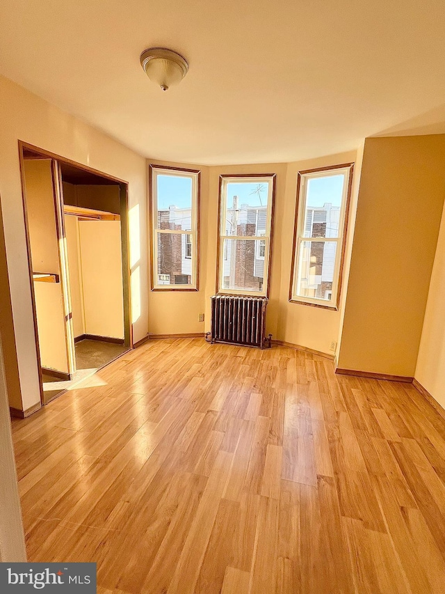 unfurnished bedroom featuring light wood-style floors, radiator, and multiple windows