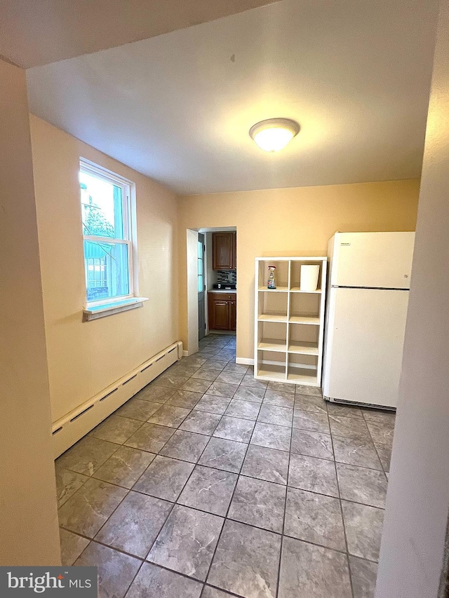 empty room with a baseboard heating unit and light tile patterned floors