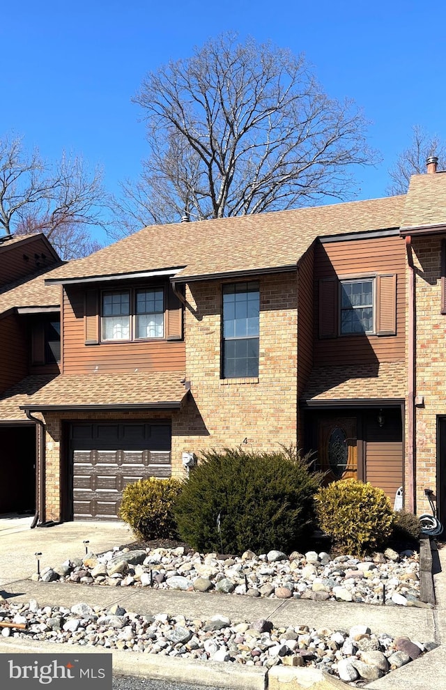 view of front of house with a garage, brick siding, concrete driveway, and a shingled roof