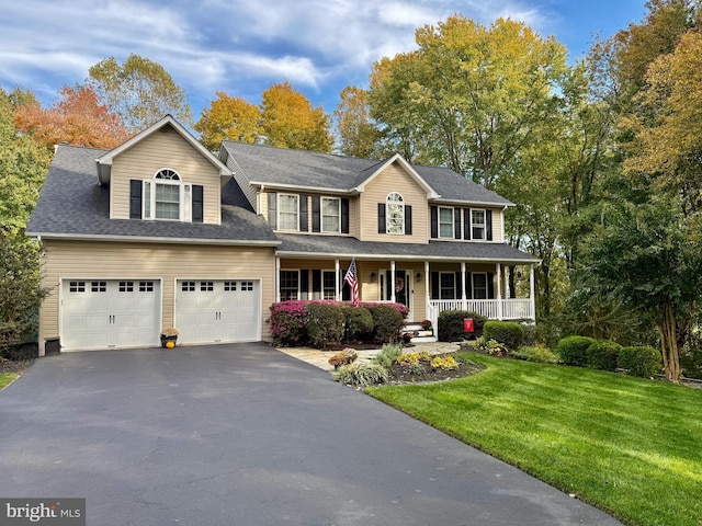 colonial inspired home with a porch, a front yard, a shingled roof, and aphalt driveway