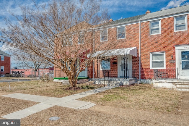 townhome / multi-family property featuring a front yard, brick siding, and a chimney