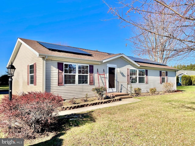 single story home with a front yard, roof with shingles, and solar panels