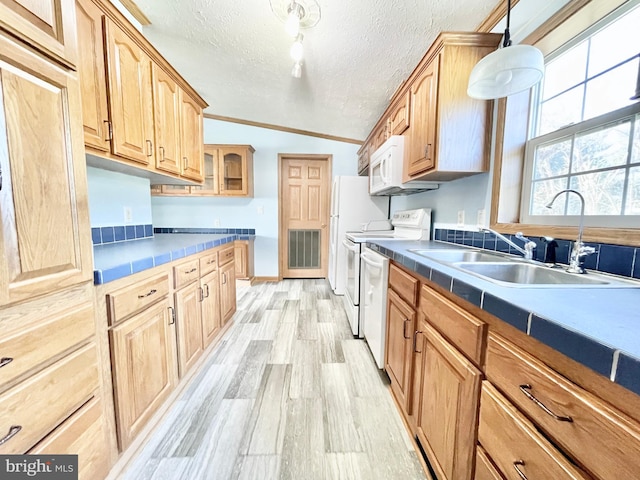 kitchen with tile counters, light wood-style flooring, a sink, a textured ceiling, and white appliances