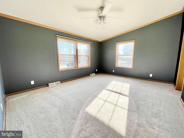 carpeted spare room with vaulted ceiling, ornamental molding, visible vents, and baseboards