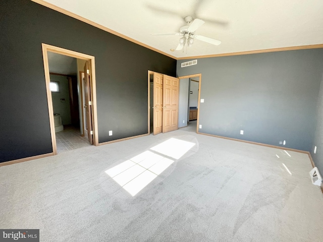 unfurnished bedroom with light colored carpet, visible vents, baseboards, ensuite bath, and crown molding