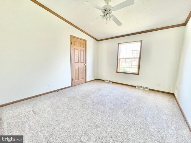 spare room featuring lofted ceiling, visible vents, and crown molding