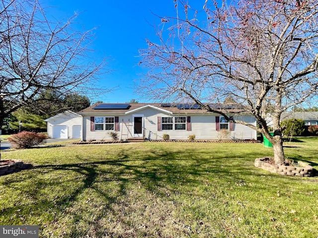 ranch-style home featuring entry steps, roof mounted solar panels, an outbuilding, and a front yard