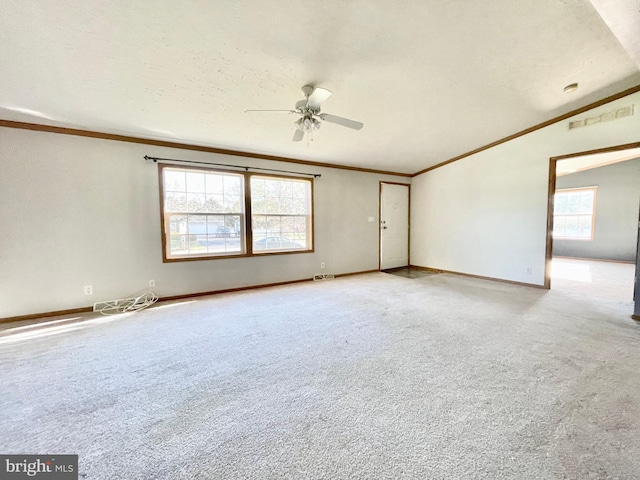 empty room with crown molding, light colored carpet, visible vents, a ceiling fan, and baseboards