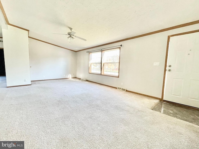 carpeted spare room featuring visible vents, crown molding, a textured ceiling, and baseboards