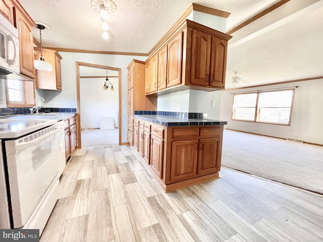 kitchen with white appliances, dark countertops, crown molding, a textured ceiling, and a sink